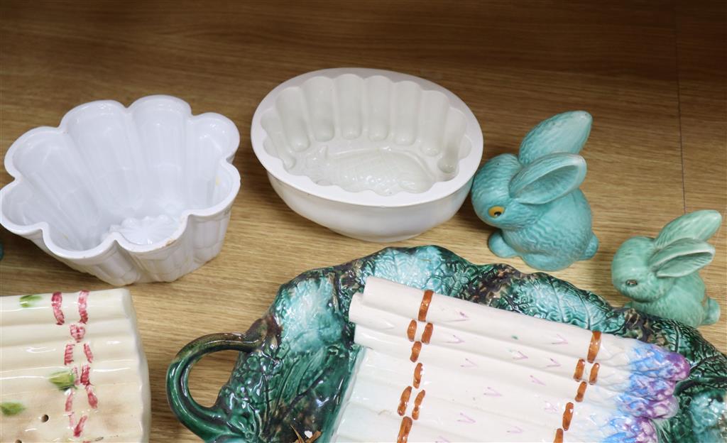 A Majolica style asparagus stand, a dish, graduated rabbits, a celery dish, and two jelly moulds, largest width 40cm
